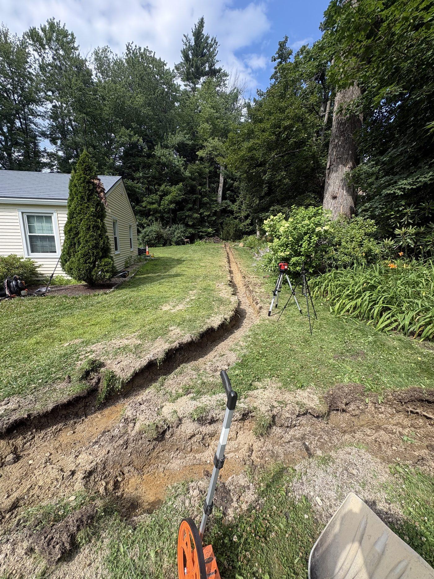 French drain trench cut with a laser level set up alongside